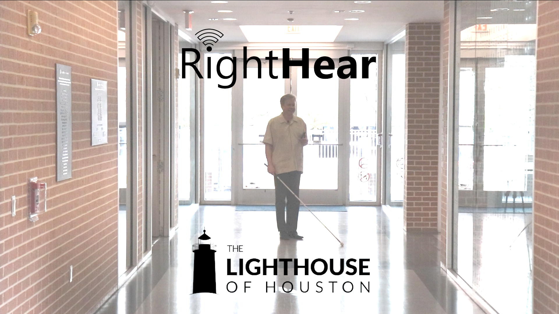 A man with a white cane standing in the main hallway at The Lighthouse of Houston. There are two black logos for RightHear and The Lighthouse of Houston.