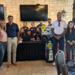 Jenna Dhayer with NWP owners and volunteers standing with raffle prizes at the golf tournament.
