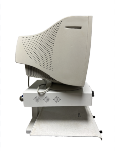 A beige CRT monitor is shown from the side, mounted on a white stand with a keyboard tray.