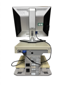 The back view of a Dell monitor on a stand, showing various ports and labels on the stand's base. The monitor has the number 004 written on its back. The stand has a beige top and a gray base.