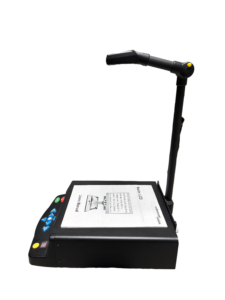 A SARA CE device with a users manual open on top, a camera on a stand above it, and control buttons on the front.