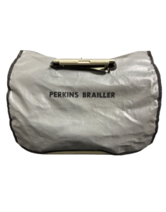 A silver case with the words PERKINS BRAILLER printed in black text. It has a handle on top.